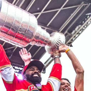 Miami Dolphins running back Raheem Mostert is joined by Florida Panthers forward Carter Verhaeghe as he raises the Stanley Cup during the Panthers' championship celebration on Fort Lauderdale Beach.