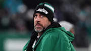 Former New York Jets quarterback Aaron Rodgers sits on the sidelines.
