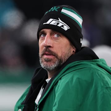 Former New York Jets quarterback Aaron Rodgers sits on the sidelines.