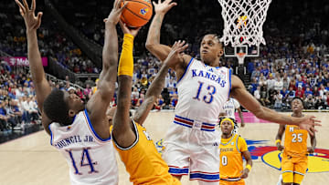 Dec 7, 2025; Kansas City, Missouri, USA; Missouri Tigers guard Sebastian Mack (12) shoots against Kansas Jayhawks guard Melvin Council Jr. (14) and guard Elmarko Jackson (13) during the second half at T-Mobile Center. Mandatory Credit: Jay Biggerstaff-Imagn Images