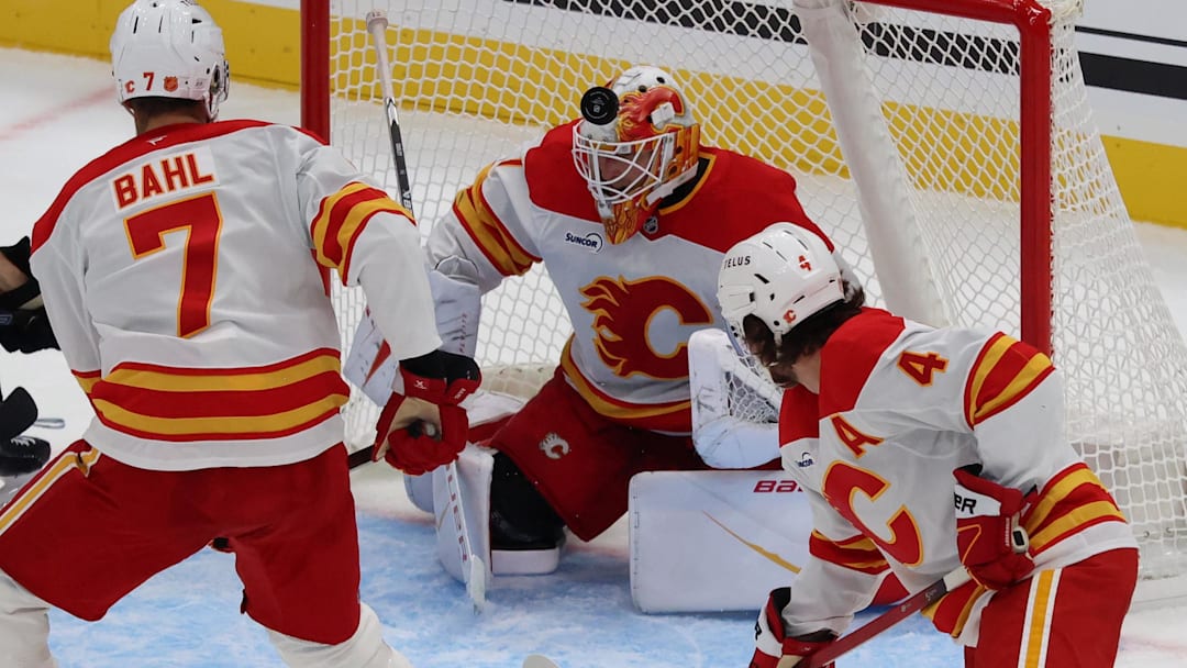 Oct 15, 2025; Salt Lake City, Utah, USA; Calgary Flames goaltender Devin Cooley (1) blocks a shot by the Utah Mammoth during the second period at Delta Center. Mandatory Credit: Rob Gray-Imagn Images