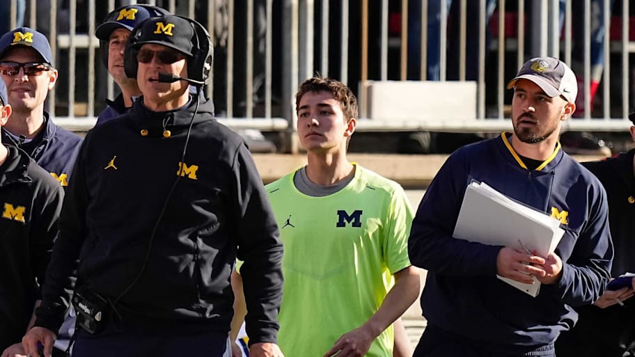 Michigan Wolverines head coach Jim Harbaugh (left) watches from the sideline near off-field analyst Connor Stalions (right).