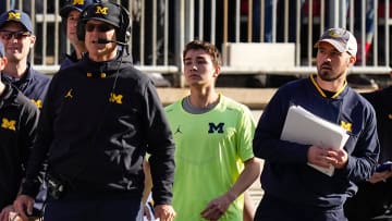 Michigan Wolverines head coach Jim Harbaugh watches from the sideline beside off-field analyst