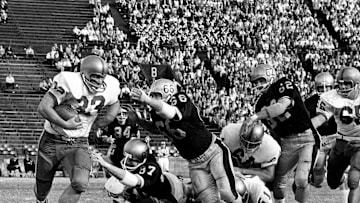 Miami Hurricanes running back Doug McGee (33) is facing two diving Vanderbilt defenders, Steve Skupas (87) and Jimmy Wyatt (66). Rugged Miami defeated the Commodores 28-14 before 12,996 die-hard fans at Dudley Field on Nov. 13, 1965.
