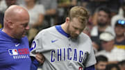 Milwaukee, Wisconsin, USA; Chicago Cubs outfielder Ian Happ (8) is helped off the field by a Chicago Cubs trainer after fouling a ball off his foot against the Milwaukee Brewers in the eighth inning at American Family Field. Happ did not return to bat after being taken out of the game.