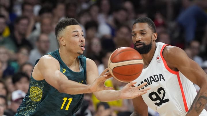 Jul 30, 2024; Villeneuve-d'Ascq, France; Australia point guard Dante Exum (11) passes the ball away from Canada centre Khem Birch (92) in a men's group stage basketball match during the Paris 2024 Olympic Summer Games at Stade Pierre-Mauroy. Mandatory Credit: John David Mercer-USA TODAY Sports