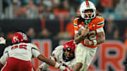 Nov 15, 2025; Miami Gardens, Florida, USA; Miami Hurricanes running back Girard Pringle Jr. (22) carries the football against NC State Wolfpack defensive back Asaad Brown Jr. (26) during the fourth quarter at Hard Rock Stadium. Mandatory Credit: Sam Navarro-Imagn Images