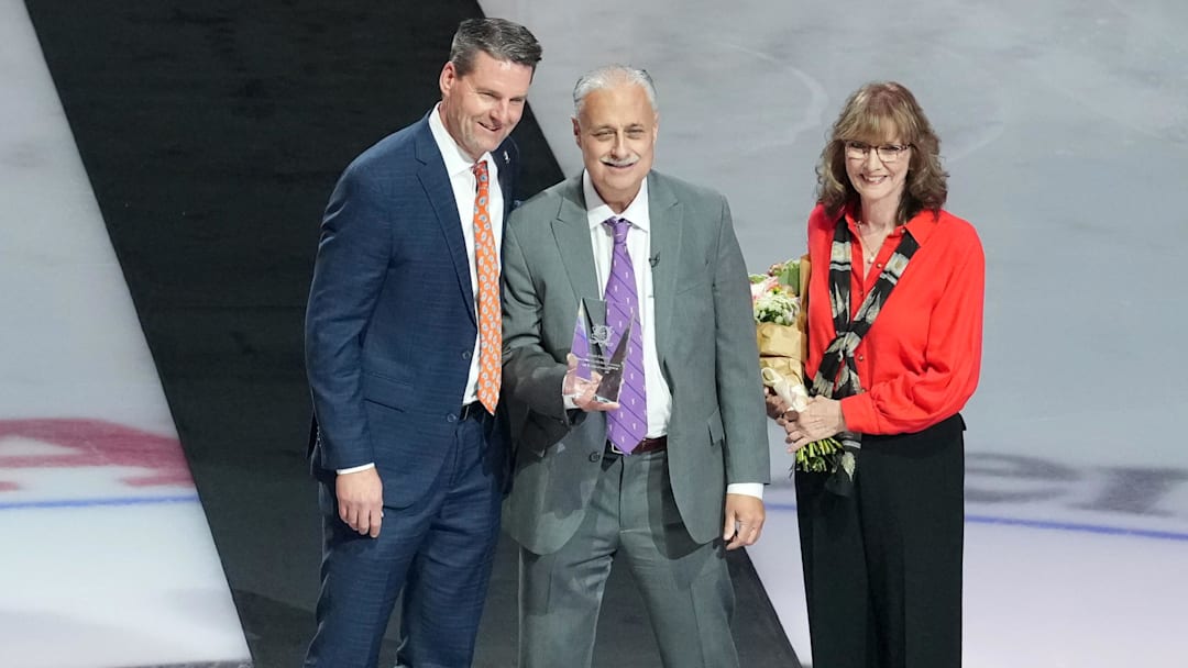 Dec 19, 2025; Anaheim, California, USA; Anaheim Ducks radio broadcaster Steve Carroll (center) poses with wife Rhonda Carroll (right) and Ducks president Aaron Teats to honor Carroll's career broadcast before the game against the Dallas Stars at the Honda Center. Mandatory Credit: Kirby Lee-Imagn Images