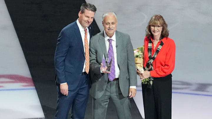 Dec 19, 2025; Anaheim, California, USA; Anaheim Ducks radio broadcaster Steve Carroll (center) poses with wife Rhonda Carroll (right) and Ducks president Aaron Teats to honor Carroll's career broadcast before the game against the Dallas Stars at the Honda Center. Mandatory Credit: Kirby Lee-Imagn Images