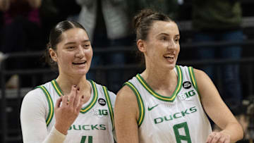 Oregon’s Nani Falatea, left, and Elisa Mevius celebrate as they leave the court in the lead against Wisconsin at the half.