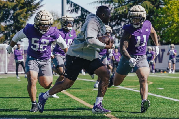 Voi Tunuufi (52) and Alphonzo Tuputala (11) chase after a ball-carrying coach in spring ball. 