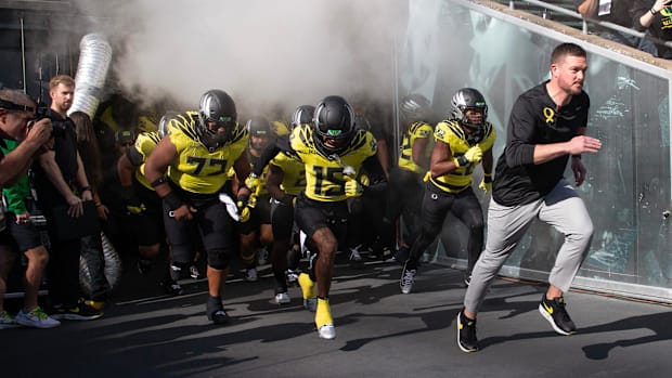 Oregon coach Dan Lanning leads his team onto the field veer their game against Illinois at Autzen Stadium