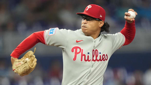 Philadelphia Phillies pitcher Jesus Luzardo throws in a gray uniform, red long sleeves and red hat