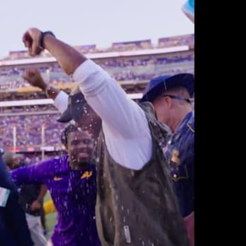 LSU interim head coach Frank Wilson raises his hands in the air after earning his first coaching victory for the Tigers.