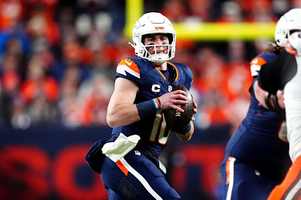 Denver Broncos quarterback Bo Nix (10) drops back to pass in a navy jersey.