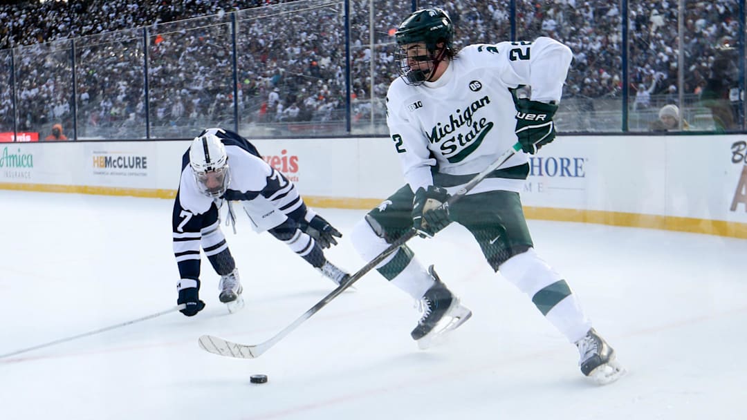Jan 31, 2026; State College, PA, USA; Michigan State Spartans forward Porter Martone (22) moves the puck against Penn State Nittany Lions defenseman Jackson Smith (7) during the second period at Beaver Stadium.
