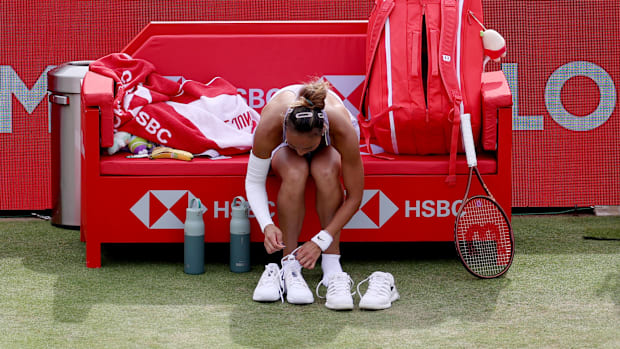 Qinwen Zheng changes tennis shoes on the court.