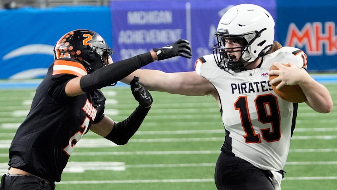 Harbor Beach (19) Caden Bucholtz stiff arms Hudson (2) Bradley Pickford from stopping his run during first half action in the MHSAA Division 8 football championship between Harbor Beach and Hudson at Ford Field in Detroit on Friday, Nov. 28, 2025.