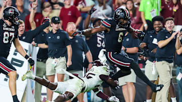 Nov 2, 2024; Columbia, South Carolina, USA; South Carolina Gamecocks tight end Joshua Simon (6) jumps over Texas A&M Aggies defensive back Dalton Brooks (25) while running on a touchdown reception in the second half at Williams-Brice Stadium. Mandatory Credit: Jeff Blake-Imagn Images