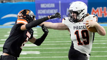 Harbor Beach (19) Caden Bucholtz stiff arms Hudson (2) Bradley Pickford from stopping his run during first half action in the MHSAA Division 8 football championship between Harbor Beach and Hudson at Ford Field in Detroit on Friday, Nov. 28, 2025.