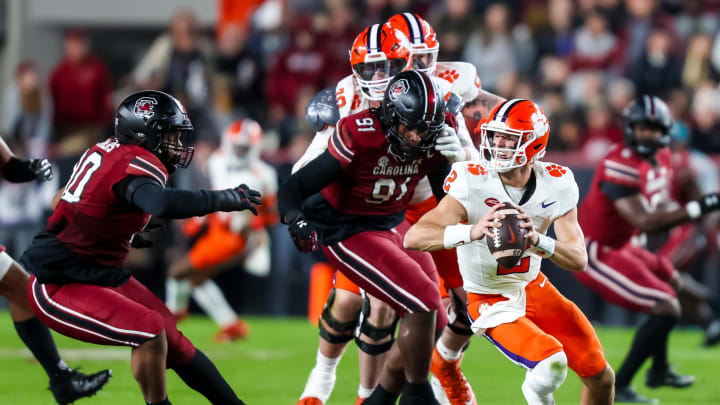 Nov 25, 2023; Columbia, South Carolina, USA; Clemson Tigers quarterback Cade Klubnik (2) scrambles under pressure from South Carolina Gamecocks defensive tackle T.J. Sanders (90) and defensive tackle Tonka Hemingway (91) in the first quarter at Williams-Brice Stadium. Mandatory Credit: Jeff Blake-USA TODAY Sports