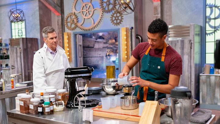 Host John Henson interacts with Contestant Aaron Davis on Food Network's Halloween Baking Championship