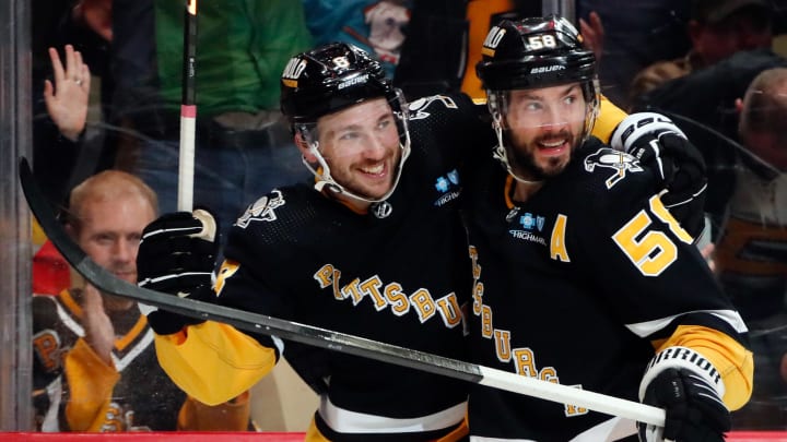 Pittsburgh Penguins left wing Michael Bunting (8) and defenseman Kris Letang (58) celebrate a goal by Letang against the Detroit Red Wings during the first period at PPG Paints Arena.