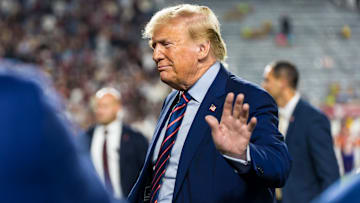 Nov 25, 2023; Columbia, South Carolina, USA; Former President Donald Trump waves as he leaves the field with South Carolina Governor Henry McMaster during halftime of a game between the South Carolina Gamecocks and Clemson Tigers at Williams-Brice Stadium. Mandatory Credit: Jeff Blake-Imagn Images