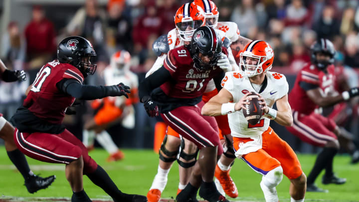 Nov 25, 2023; Columbia, South Carolina, USA; Clemson Tigers quarterback Cade Klubnik (2) scrambles under pressure from South Carolina Gamecocks defensive tackle T.J. Sanders (90) and defensive tackle Tonka Hemingway (91) in the first quarter at Williams-Brice Stadium. Mandatory Credit: Jeff Blake-USA TODAY Sports