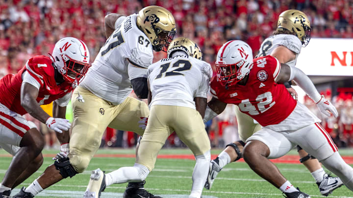 Nebraska defenders Jimari Butler and Mikai Gbayor converge to bring down Colorado's Travis Hunter.