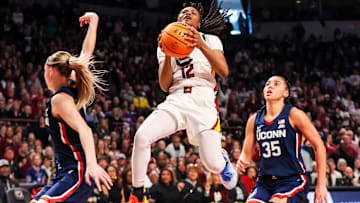 Feb 16, 2025; Columbia, South Carolina, USA; South Carolina Gamecocks guard MiLaysia Fulwiley (12) drives between UConn Huskies guard Paige Bueckers (5) and guard Azzi Fudd (35) in the first half at Colonial Life Arena. Mandatory Credit: Jeff Blake-Imagn Images