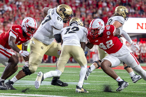 Nebraska defenders Jimari Butler and Mikai Gbayor converge to bring down Colorado's Travis Hunter.