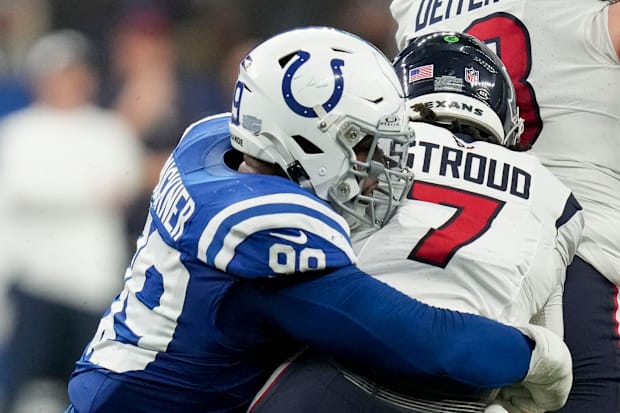 Indianapolis Colts defensive tackle DeForest Buckner sacks Houston Texans quarterback C.J. Stroud in a blue jersey.