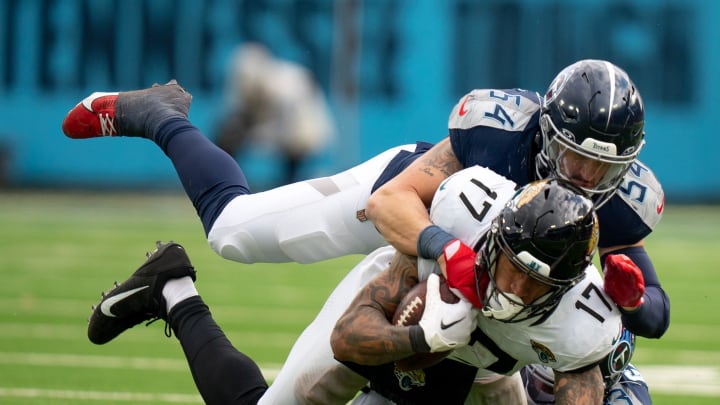 Jacksonville Jaguars tight end Evan Engram (17) is brought down after a catch by Garret Wallow (54) and Tennessee Titans cornerback Eric Garror (33) during their game at Nissan Stadium in Nashville, Tenn., Sunday, Jan. 7, 2024.