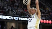 Akron Zips forward James Okonkwo (32) hangs on the rim after a dunk during the second half of an NCAA college basketball game in the semifinals of the Mid-American Conference Tournament at Rocket Arena on Friday, March 14, 2025, in Cleveland, Ohio.