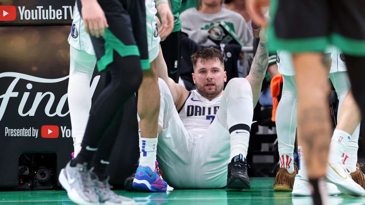 Dallas Mavericks guard Luka Doncic (77) is helped up after a play against the Boston Celtics during the third quarter in game two of the 2024 NBA Finals at TD Garden.