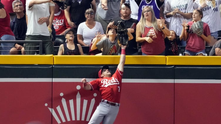 Cincinnati Reds left fielder Spencer Steer leaps at the wall.