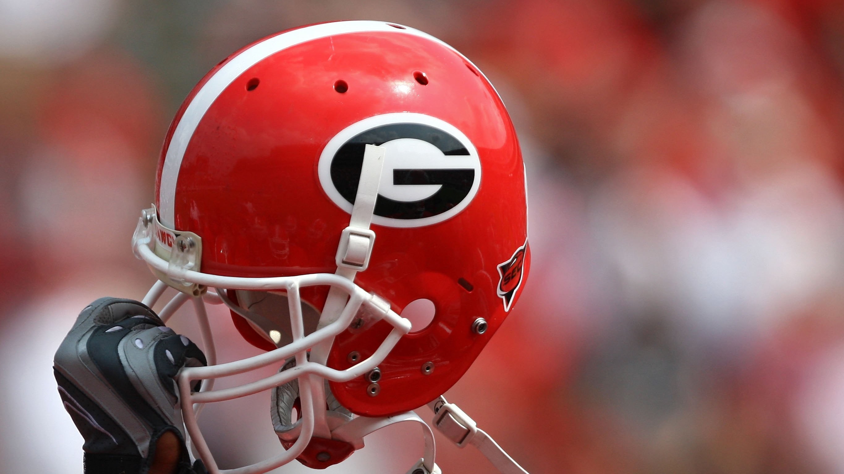 A member of the Georgia Bulldogs football team raises his helmet during a college football game in the SEC.