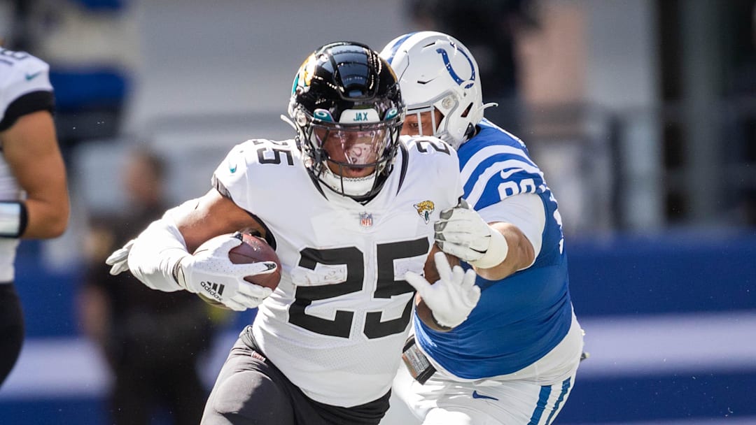 Oct 16, 2022; Indianapolis, Indiana, USA; Jacksonville Jaguars running back James Robinson (25) runs the ball while Indianapolis Colts defensive tackle Grover Stewart (90) defends  in the first quarter at Lucas Oil Stadium. Mandatory Credit: Trevor Ruszkowski-Imagn Images