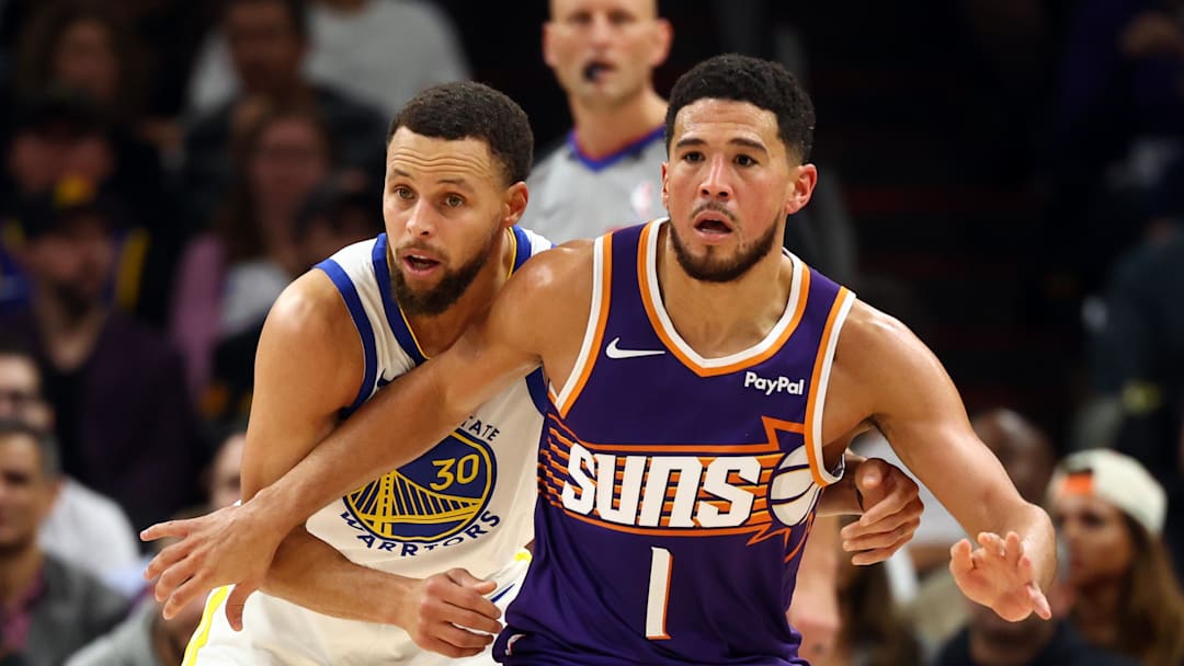 Phoenix Suns guard Devin Booker against Golden State Warriors guard Stephen Curry in the first half at Mortgage Matchup Center.