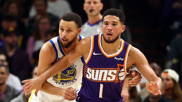 Phoenix Suns guard Devin Booker against Golden State Warriors guard Stephen Curry in the first half at Mortgage Matchup Center.