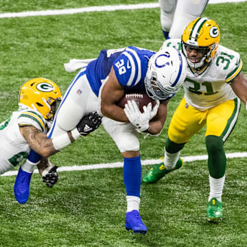 Indianapolis Colts running back Jonathan Taylor (28) is tackled by Green Bay Packers cornerback Jaire Alexander (23) and strong safety Adrian Amos (31)  in the second half at Lucas Oil Stadium in 2020.