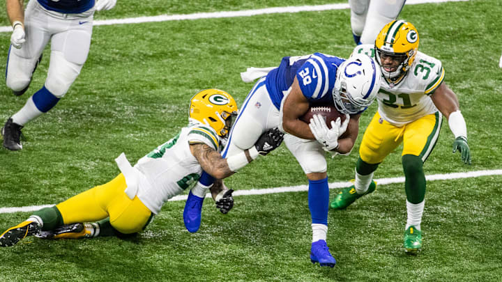 Indianapolis Colts running back Jonathan Taylor (28) is tackled by Green Bay Packers cornerback Jaire Alexander (23) and strong safety Adrian Amos (31)  in the second half at Lucas Oil Stadium in 2020.