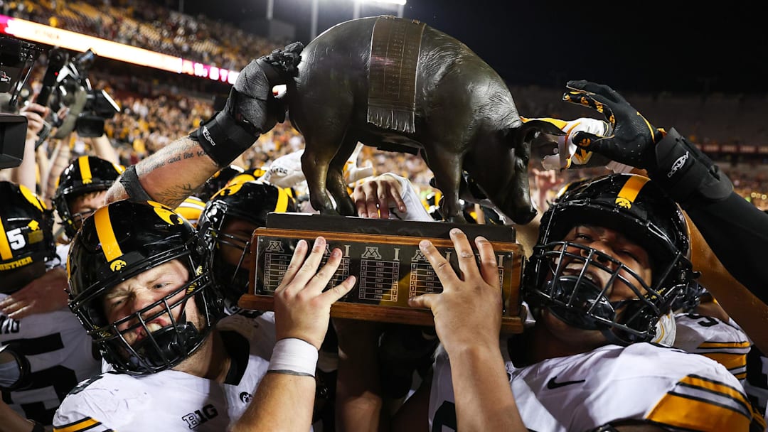 Sep 21, 2024; Minneapolis, Minnesota, USA; Iowa Hawkeyes offensive lineman Logan Jones (65) and defensive lineman Yahya Black (94) celebrate with the Floyd of Rosedale trophy after the game against the Minnesota Golden Gophers at Huntington Bank Stadium. Mandatory Credit: Matt Krohn-Imagn Images