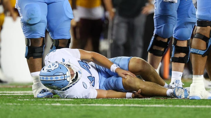 Aug 29, 2024; Minneapolis, Minnesota, USA; North Carolina Tar Heels quarterback Max Johnson (14) grabs his knee after being tackled during the second half against the Minnesota Golden Gophers at Huntington Bank Stadium. Mandatory Credit: Matt Krohn-USA TODAY Sports