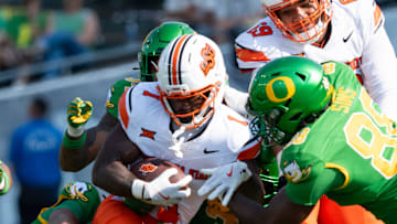 Oklahoma State running back Kalib Hicks is brought down by a pack of Oregon defenders as the Oregon Ducks host the Oklahoma State Cowboys on Sept. 6, 2025, at Autzen Stadium in Eugene, Oregon.