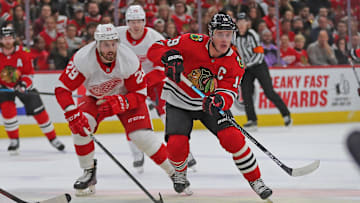 Jan 5, 2020; Chicago, Illinois, USA; Chicago Blackhawks center Jonathan Toews (19) makes a pass with Detroit Red Wings left wing Brendan Perlini (29) in pursuit during the first period at the United Center. Mandatory Credit: Dennis Wierzbicki-Imagn Images