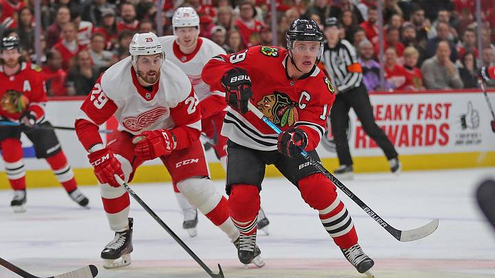 Jan 5, 2020; Chicago, Illinois, USA; Chicago Blackhawks center Jonathan Toews (19) makes a pass with Detroit Red Wings left wing Brendan Perlini (29) in pursuit during the first period at the United Center. Mandatory Credit: Dennis Wierzbicki-Imagn Images