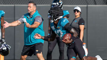 Jacksonville Jaguars wide receiver Travis Hunter (12) runs a drill as Jacksonville Jaguars Defensive Coordinator Anthony Campanile watches during the Jaguars 14th NFL training camp session at Miller Electric Center Tuesday August 12, 2025 in Jacksonville, Fla. The Jaguars travel to New Orleans to play the Saints this Sunday in their second preseason game. 