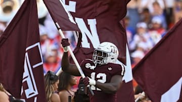 Oct 11, 2025; College Station, Texas, USA; Texas A&M Aggies defensive end Nana Boadi-Owusu (12) runs out with the 12th Man flag prior to the game against the Florida Gators at Kyle Field. Mandatory Credit: Maria Lysaker-Imagn Images 